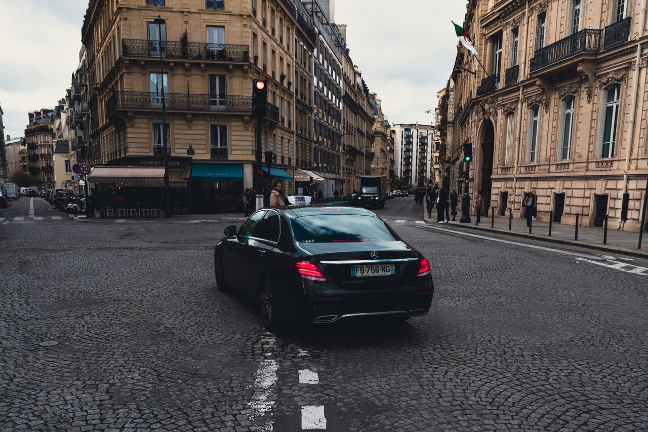 Elegant black Mercedes-Benz taxi driving through charming Paris streets, highlighting urban sophistication.