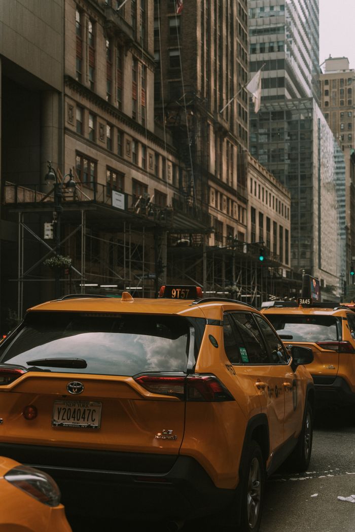 A busy street scene featuring iconic yellow taxis and tall city buildings in an urban setting.